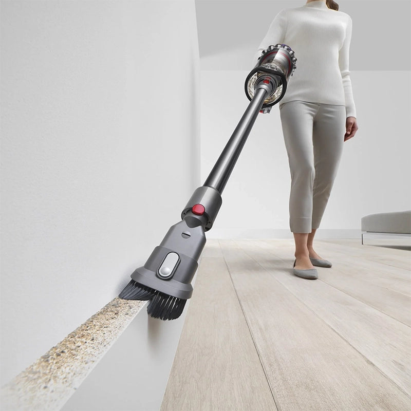 Dyson Outsize Extra cordless stick vacuum cleaning along wall edges